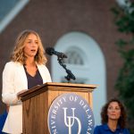 Nikki Dombrowski speaks at the 2016 Twilight Induction Ceremony. She is standing at a podium with the University of Delaware logo on it.