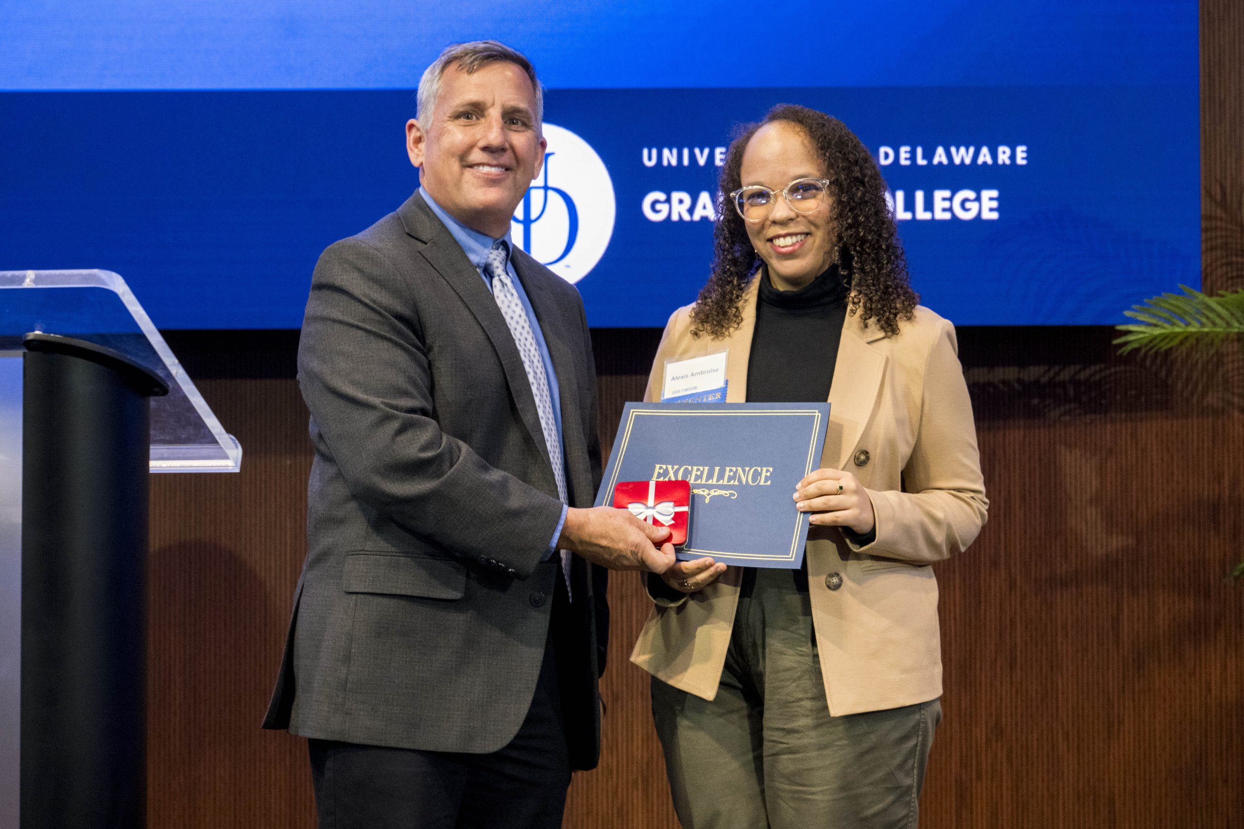 HDFS Ph.D. Student Alexis Ambroise standing with her award with Dean Lou Rossi.