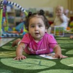 A child plays on the floor in the Early Learning Center’s infant classroom.