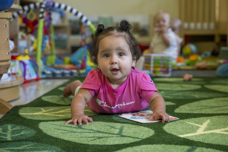 A child plays on the floor in the Early Learning Center’s infant classroom.